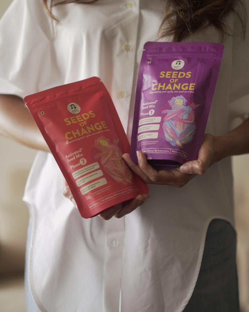 Woman in a white shirt holding the two Seeds of Change pouches